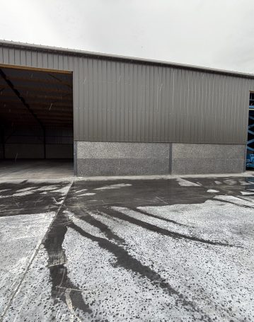 Hangar agricole en acier gris avec nacelle élévatrice en cours d’installation de porte sectionnelle.