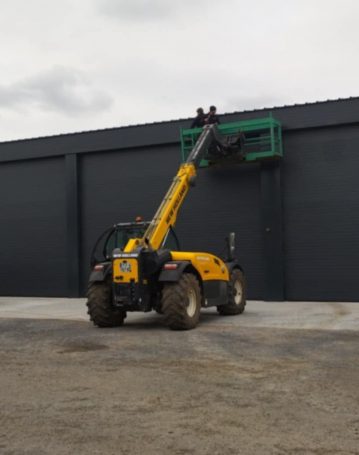 Installation de portes industrielles sur hangar métallique à l’aide d’une nacelle télescopique.